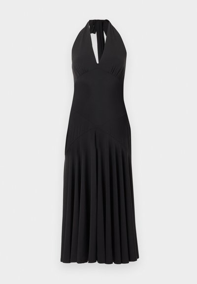 Robe midi noire à col licou avec un profond décolleté en V et une jupe plissée sur un fond clair uni.
