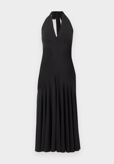 Robe midi noire à col licou avec un profond décolleté en V et une jupe plissée sur un fond clair uni.