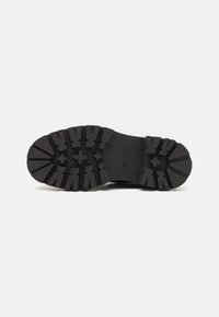 Rubber sole with deep tread design, featuring alternating horizontal and vertical grooves. Text insole reads "ALDO." Solid black color.