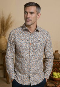 Overhemd met knoopsluiting van lichtgewicht stof, voorzien van een bloemenpatroon in oranje en marineblauw op een witte achtergrond, met lange mouwen en een klassieke kraag.