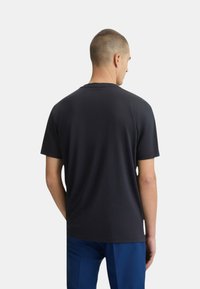 T-shirt nera a maniche corte con colletto rotondo. Realizzata in tessuto di cotone, presenta una texture liscia e una vestibilità rilassata.