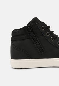 Schwarze High-Top-Sneaker mit einem strukturierten Stoff-Obermaterial, seitlichem Reißverschluss und weißer Gummisohle. Verfügt über Metallösen und einen gepolsterten Knöchelkragen.