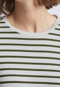 Weißes Baumwoll-T-Shirt mit horizontalen olivgrünen Streifen, mit rundem Ausschnitt und weicher, glatter Textur.