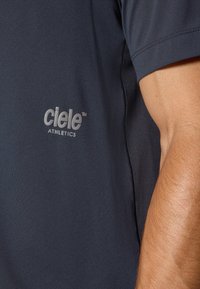Dark navy athletic shirt featuring a smooth texture, short sleeves, and a reflective "ciele ATHLETICS" logo on the front.