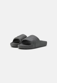 Schwarze Flip-Flops mit offenem Zehenbereich, strukturiertem Oberflächenmaterial und welligem Muster; aus flexiblem Material gefertigt, mit konturiertem Design für Komfort.