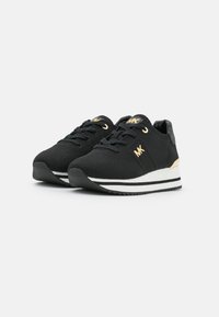 Czarne sportowe buty z teksturowaną górą z dzianiny, złotymi detalami, białą i czarną paskowaną podeszwą środkową oraz czarną gumową podeszwą.