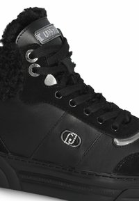 Sneaker alta nera con sopra in tessuto felpato, dettagli in pelle, occhielli in metallo e un logo decorativo in strass sul lato.
