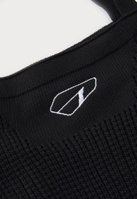 Căciulă tricotată neagră, cu un logo alb brodat. Textura este ribbed, oferind o potrivire strânsă și o cusătură plată pe margine.