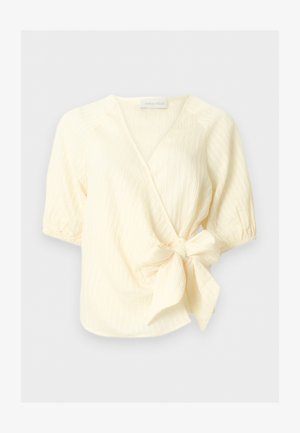 Kremasta bluza z dolgimi rokavi kratkih rokavov, z V-izrezom in teksturiranim materialom, z veliko stransko pentljo in elastičnimi robčki na rokavih.