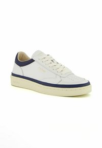 Sneaker in pelle bianca con dettagli blu navy, punta rotonda, tomaia perforata, lacci piatti e suola in gomma texture. Logo del marchio in oro.
