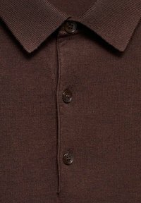 Brązowa dzianinowa koszulka polo z płaskim kołnierzem, wyposażona w trzy ciemnobrązowe guziki oraz prążkowaną teksturę na całej tkaninie.