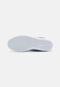 Shoe sole with a textured herringbone pattern in white rubber, featuring a black accent on the side and a grey Nike logo.