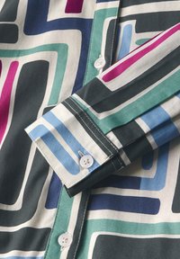 Hemd mit Kragen aus weichem Stoff mit kräftigen geometrischen Mustern in Türkis, Marineblau, Lila und Weiß. Verfügt über Knöpfe und kontrastierende Nähte.