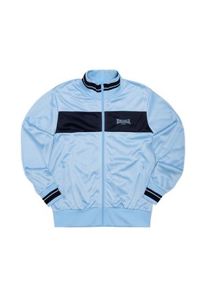 Lichtblauw trainingsjack met ritssluiting, een marineblauw paneel over de borst, een geribbelde kraag en manchetten, en zijzakken met een subtiel logodetail.
