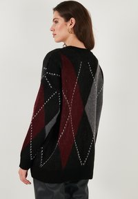 Pulover tricotat negru cu un model argyle în blocuri de culoare gri, vișiniu și roșu, cu manșete ribbate și o croială lejeră.