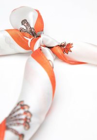 Hedvábný šátek s oranžovými a bílými pruhy, zdobený detailním vzorem chobotnice a listů, uvázaný do uzlu. Hladká textura.