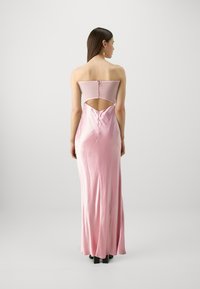 Svetloružová saténová večerná šaty s bezramienkovým dizajnom, odhaleným chrbtom a elegantnou siluetou. Obsahuje vertikálny šev a zips.