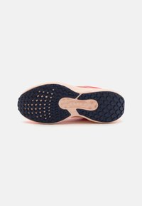 Die Schuhsohle verfügt über eine Gummisohle mit einer strukturierten Grip-Oberfläche in Marineblau, die sich von einer pinken Zwischensohle und integrierten Dämpfungselementen abhebt.