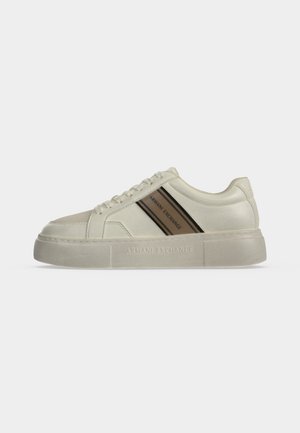 Baskets basses blanches avec une bande diagonale beige et noire et marquage "Armani Exchange" sur la semelle et le panneau latéral, fermeture à lacets.
