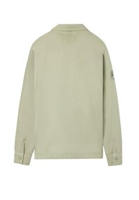 Camisa de manga larga verde claro con cuello, cierre frontal con botones y detalle de logo en la manga izquierda. Tejido de algodón suave, corte relajado.