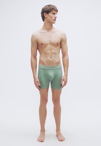 Πράσινα βαμβακερά μποξεράκια με ελαστική μέση που φέρει το λογότυπο "GAP". Λεία υφή, εφαρμοστή γραμμή και μήκος μέχρι το μέσο του μηρού.