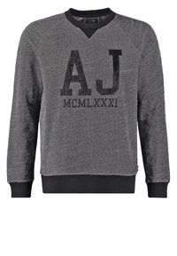 Felpa grigia in tessuto testurizzato, con scollo a V, polsini e orlo a costine neri, e una grafica nera audace con la scritta "AJ MCMLXXXI."