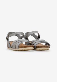 Sandalias de cuero gris con múltiples correas, hebilla ajustable en el tobillo, plantilla de corcho texturizada y una suela de goma ligera con patrón de tracción.