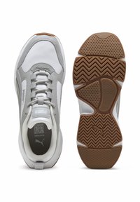Scarpe da ginnastica bianche e grigie con una tomaia in mesh, suole in gomma testurizzate e un motivo a zigzag sul battistrada. Presentano un collare imbottito e chiusura con lacci.