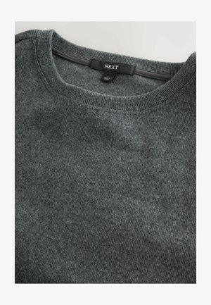 Jersey gris de punto con un escote redondo y una textura suave. La etiqueta dice "NEXT". La tela parece lisa con un ligero brillo.