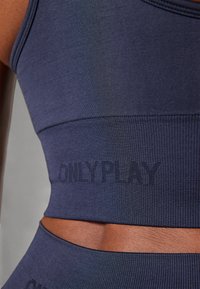 Marineblå sport BH laget av elastisk stoff, med ribbet tekstur og en "ONLY PLAY"-logo preget på båndet.