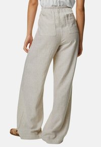 Wijde broek van een lichte stof met verticale beige en witte strepen. Beschikt over een elastische tailleband en twee achterzakken.