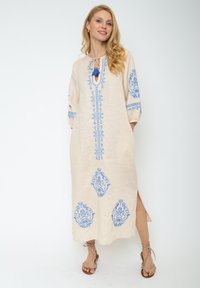 Beiges Leinen-Midi-Kleid mit blauen Blumenstickereien, rundem Ausschnitt, Schlüssellochdetail, Dreiviertelärmeln und seitlichen Schlitzen.