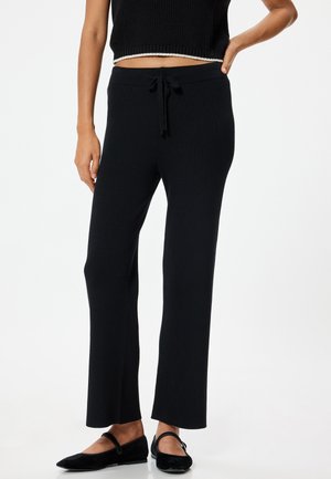 Zwarte geribde loungebroeken van rekbaar materiaal, met een drawstring taille en een recht model. Geen opvallende patronen of accenten.