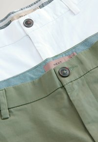 Dos pares de pantalones: uno en blanco y el otro en verde oliva. Cada uno cuenta con un cierre de botón y un forro de la cinturilla con estampado.