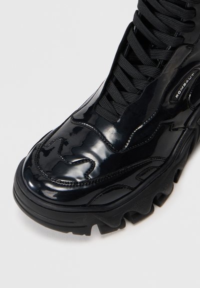 Sneaker alta in patent nero con motivi a onda testurizzati, punta rotonda e suola in gomma spessa con battistrada antiscivolo e lacci neri.