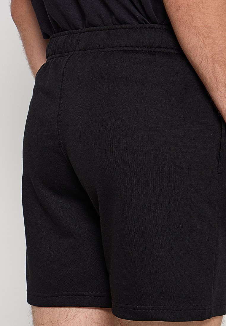 Pantalones cortos deportivos negros con una cinturilla elástica, textura de tela suave y un diseño ajustado. Sin bolsillos visibles ni patrones.