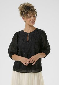 Black embroidered blouse with sheer fabric, round neckline, keyhole detail, and three-quarter puff sleeves; floral bead patterns throughout.