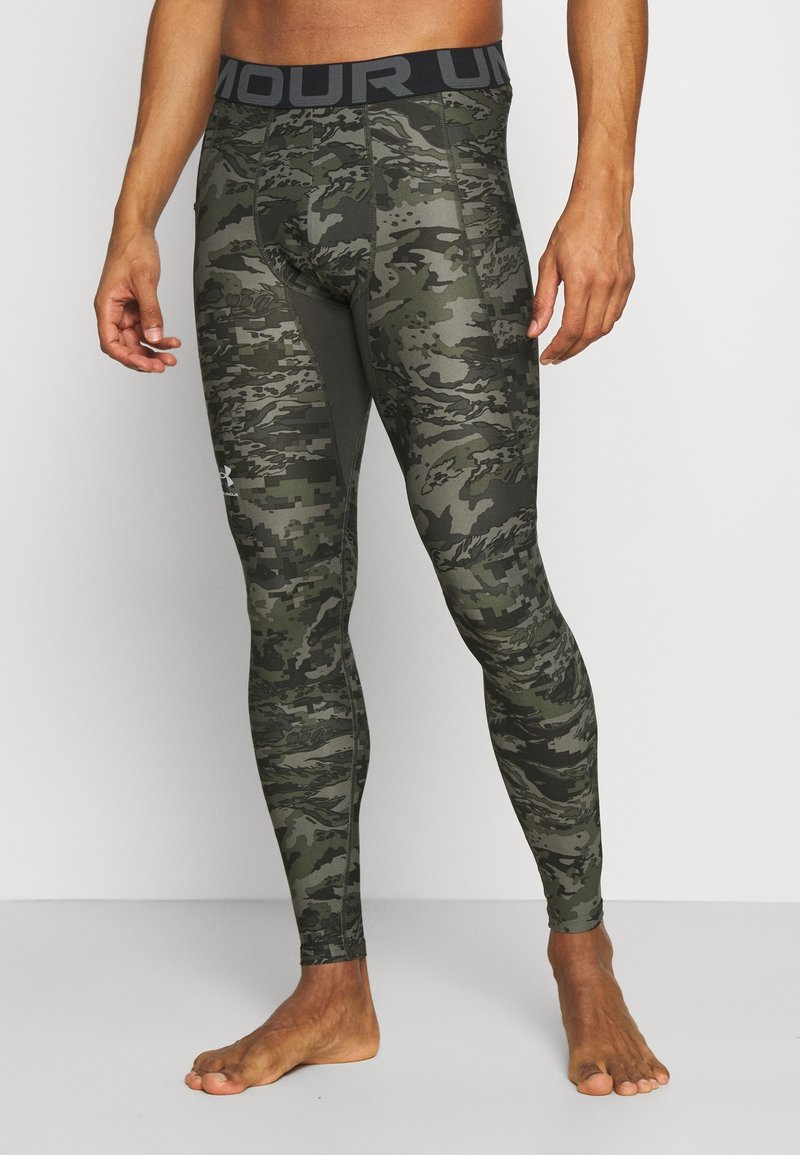 Legginsy w wzór kamuflażowy w odcieniach zieleni, z szerokim czarnym pasem w talii z napisem "ARMOUR", wykonane z elastycznego, gładkiego materiału.