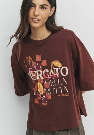 Brown cotton t-shirt with loose fit, featuring a colorful fruit-themed graphic text reading "Mercato della Frutta" and short sleeves.