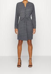Vestido azul marino con mangas largas, un frente abotonado y un lazo en la cintura. Presenta un estampado sutil y un dobladillo a la altura de la rodilla.