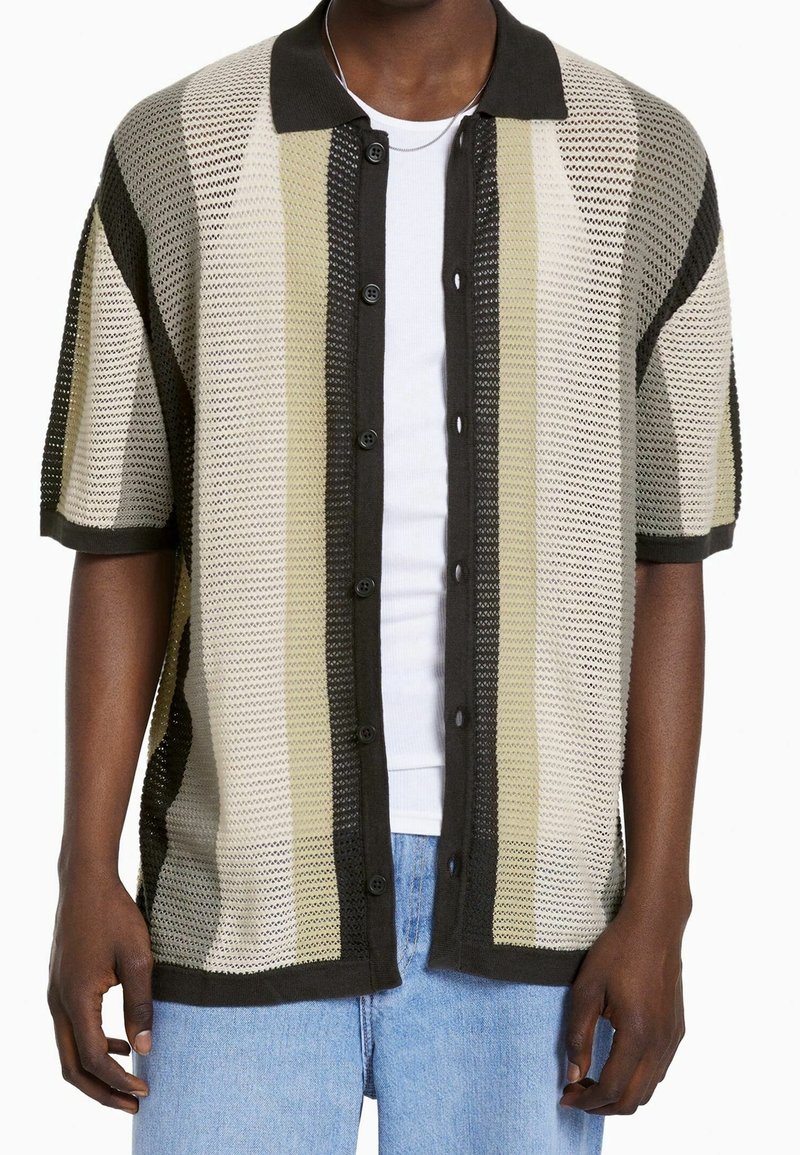 Camisa de manga corta con botones en un diseño de malla con rayas horizontales en beige, verde oliva y marrón oscuro. Presenta un collar oscuro y detalles acentuados.
