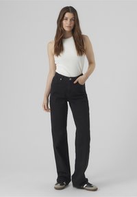 Jeans neri a vita alta con taglio dritto, in denim, cinque tasche e chiusura con bottone, abbinati a un top senza maniche bianco a costine.