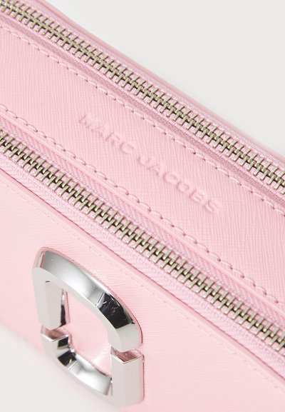 Pink leather zip wallet featuring silver hardware, textured surface, and embossed logo. The zip closure runs along the top edge.