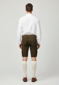 Men's olive green shorts made of soft fabric, featuring pockets and a back belt loop, paired with knee-high cream socks and brown shoes.