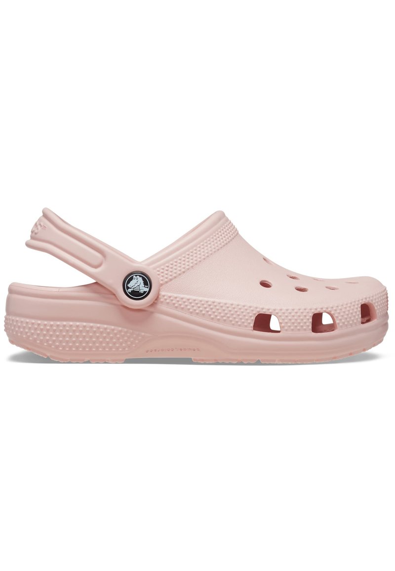 Zueco de goma de color rosa claro con agujeros de ventilación, correa trasera, lado texturizado y logotipo circular. Diseño suave con forma ergonómica para mayor comodidad.