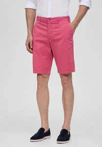 Roze katoenen shorts met een rechte snit, voorzakken en een knoopsluiting, gecombineerd met marineblauwe suède instappers.