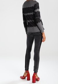 Suéter a rayas gris y negro con detalles de encaje; jeans ajustados negros; sandalias rojas de tacón cuadrado; textura lisa; ajuste casual.