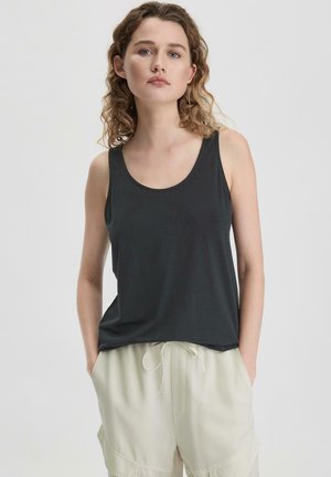 Schwarzes ärmelloses Tanktop aus weichem Stoff mit rundem Ausschnitt, kombiniert mit hellen, lässigen Hosen mit Kordelzug in der Taille.