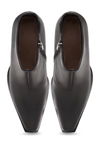 Zwarte leren schoenen met een spitse neus en contrasterende bruine binnenvoering, voorzien van een zijrits voor gemakkelijk aan- en uittrekken.