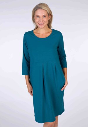 Türkises, knielanges Kleid mit rundem Ausschnitt, Dreiviertelärmeln und gefaltetem Vorderteil. Hergestellt aus weichem Stoff mit seitlichen Taschen.